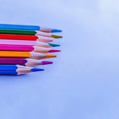 Colorful pencils arranged on light blue background