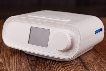 White CPAP Machine with Hose and Mask for Sleep Apnea Therapy on Dark Wooden Table