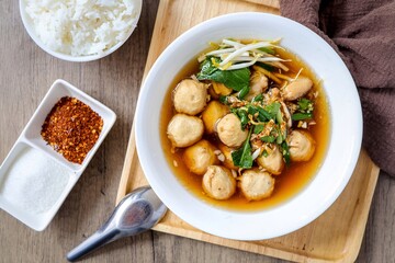 Thai style Meatball noodle soup in white bowl with cooked rice	