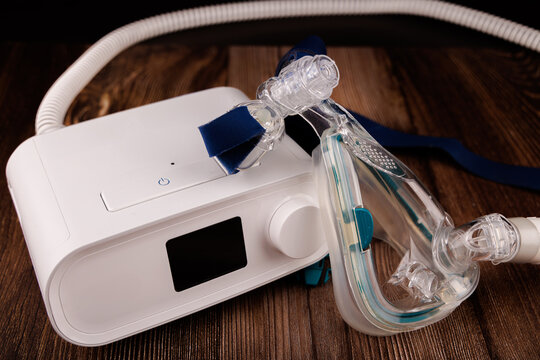 Sleep Apnea Therapy Equipment: White CPAP Machine with Display and Mask on Dark Table
