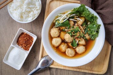 Thai style Meatball noodle soup  in white bowl with cooked rice