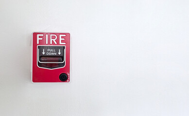 Red fire alarm pull station on white wall