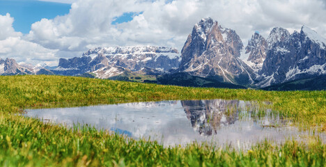 Majestic mountain landscape with scenic reflection in alpine meadow near Valley of Funes at Dolomites, Italy.