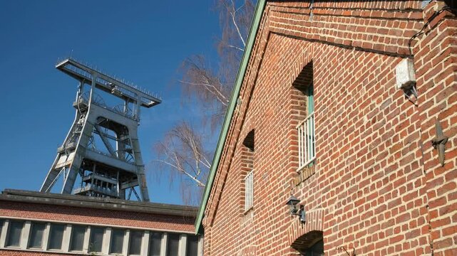 The Wallers-Arenberg coal mine features a historic red brick building and a metal headframe under a clear blue sky, showcasing France&rsquo;s industrial heritage.