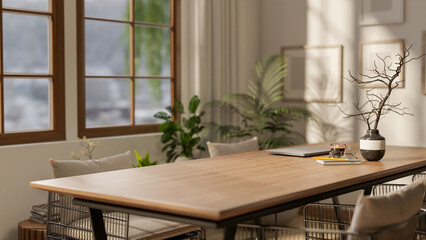 A wooden square table with decors and armchairs next to a large window with bright sunlight.