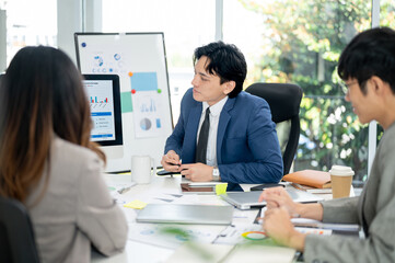 Businessman or male office worker is looking carefully at the financial report on monitor with his coworkers.