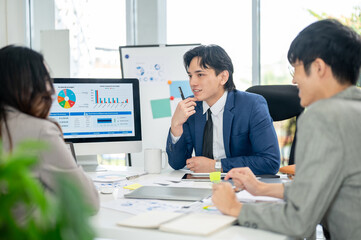 Businessman or male office worker is talking about a financial report on monitor with his coworkers.