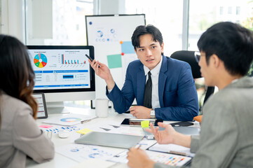Businessman or male office worker is explaining the financial report on monitor his coworkers.