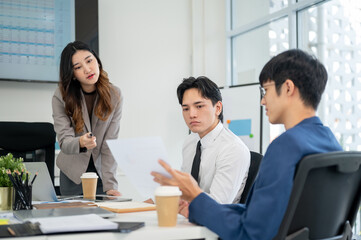 Businessman or male office worker is showing or explaining a document to his coworkers in a meeting.
