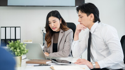 Obraz premium Female office worker is explaining data on her laptop to male coworker. business meeting or planning