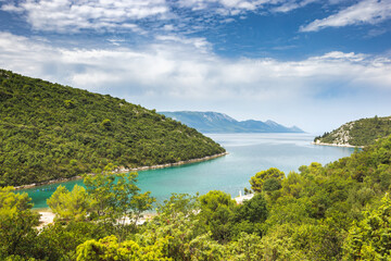The sea coast of southern Dalmatia in Croatia, Europe. Coastal Serenity: Lush green hills meet crystal waters under a bright sky, a peaceful landscape beckons exploration and tranquility.