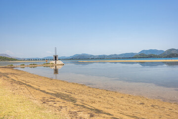 Delta of the Neretva river near the mouth of river into Adriatic Sea, Croatia, Europe. Scenic landscape featuring a calm coastline, a small building in water, and distant mountains beneath a blue sky.