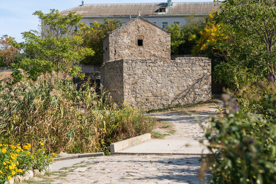 Stone building Orthodox Church is Church of Iverskaya Our Lady or Armenian Church as Church of John Baptist, surrounded by lush greenery and wildflowers. Feodosia, Crimea - September 26, 2019