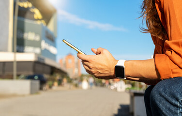 Closeup of mobile phone in woman's hands. Female checking her phone on city street