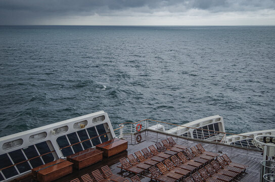 Fototapeta Views onto wet outdoor teak balcony terrace veranda promenade boat deck of ocean liner cruiseship cruise ship with chairs and loungers at sea during Transatlantic Crossing to New York