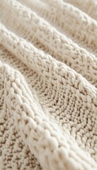 Close-up of a creamy knitted textile, showcasing its texture and intricate cable knit pattern. Soft and inviting.