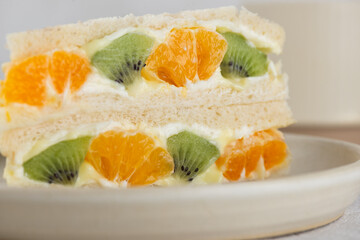 Homemade Korean sandwich with kiwi, orange and cream cheese in a plate, closeup. Asian dessert, street food.