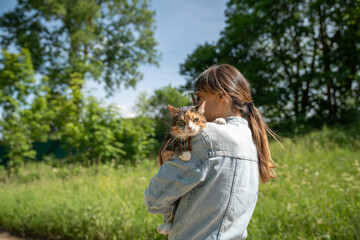 Woman holding relaxed cat in arms. Pet looking at camera, exploring territory with interest, curiosity, feeling cozy, comfortable in hands of female owner. Girl wandering with kitty together.