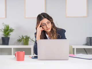 Sad thoughtful businesswoman looking aside, portrait of young caucasian thinking sad thoughtful businesswoman looking aside working in office with laptop computer. Worried about financial success.