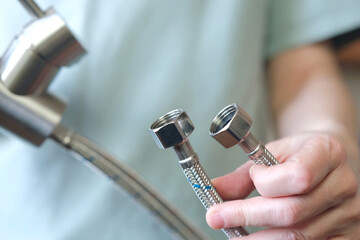 close-up of the nuts of flexible hoses for cold and hot water at the kitchen faucet. Preparing to...