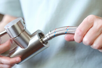 A close-up of a mixer with flexible hoses for cold and hot water installed. Preparing to replace...