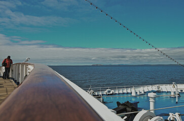 Outdoor promenade boat deck patio terrace onboard classic expedition cruiseship cruise ship liner during cruise through Orkney Islands archipelago coast line	