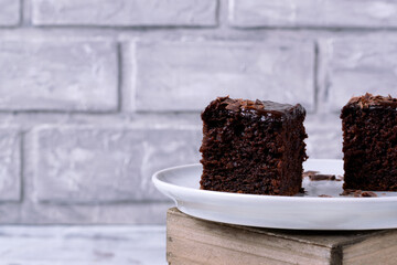 Two pieces of chocolate cake covered with ganache on a ceramic plate. Copy space. Close-up
