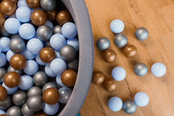 Multicolor Plastic Balls Overflowing from Circular Ball Pit on Wooden Floor