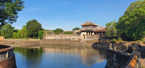 Imperial palace grounds in Hoi An, Vietnam, showcasing traditional architecture surrounded by lush greenery and calm water, reflecting historical significance and cultural heritage.