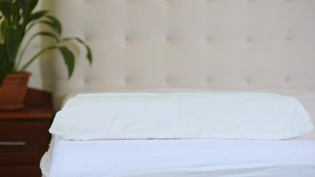 A woman in the pajama put two pillows on bed