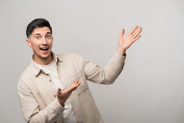 Exciting product or service presentation as a handsome man in his 30s with a big smile confidently points up and to the side with open palms, radiating happiness and trust
