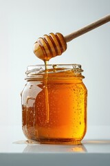 Honey dripping from wooden dipper into glass jar
