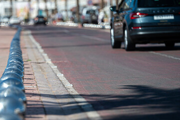 Cars drive along a clean road lined with decorative metal barriers in Morocco's urban area.