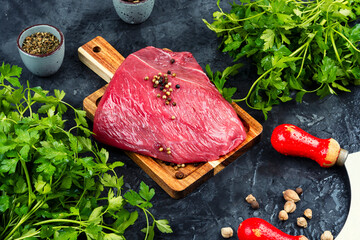 Raw beef steak on a rustic wooden board.