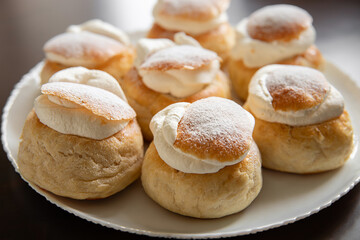 Estonia`s traditional dessert called vastlakukkel witch is popular on holiday Vastlapäev. Cute buns with whipped cream on natural wooden table in home kitchen.