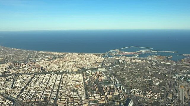 An elevated aerial view of Valencia city center and harbor, recorded from an airplane cockpit arriving at golden hour.