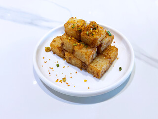 asian deep fried crispy vegetable carrot cake in square w garlic onion spices in plate on marble...