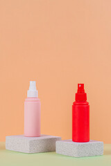 Cosmetic pink bottle. Womens cosmetic accessory for makeup with stylish props on cream background.