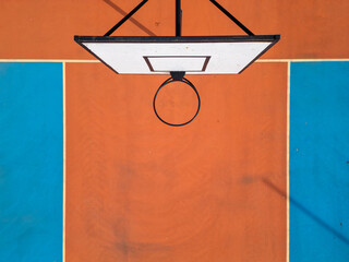 Aerial view of a basketball hoop and colorful court with vibrant orange and blue sections. The...