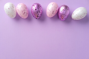 Speckled Easter eggs in pastel shades on a purple background. Minimalism style. Flat lay, top view.
