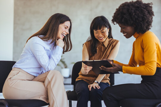 Three Women Collaborating in a Discussion with a Tablet During a Meeting
