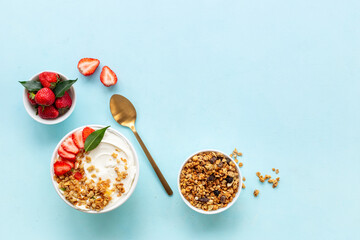 Flat lay composition with yogurt and muesli in bowl served with ingredients. Top view