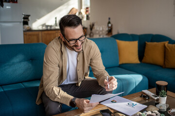 Smiling freelancer reviewing documents and charts at home office