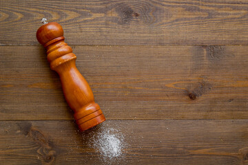 Wooden salt shaker and pile of spilled salt, top view. Cooking concept