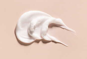 smears of creamy white texture cosmetic sample close up on beige background