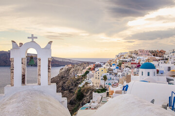 Scenic view of Oia, Santorini, Greece, featuring the iconic three domes viewpoint, colorful houses, and the Aegean Sea. Horizontal shot with a cloudy sky, perfect for honeymoon or wedding destination