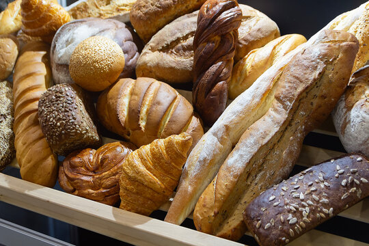 A bakery counter with an array of bread loaves, rolls, and baguettes