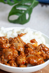 A bowl of South African street food, spicy chicken livers with traditional pap