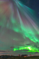 Beautiful Aurora Borealis over house on island of Hillesøya, dancing northern lights with clear colorful rays of green light in the sky with red and purple strikes! amazing joy in Norway