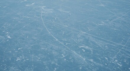 A high-angle shot captures the intricate details of an ice rink surface, revealing a network of skate marks and scratches